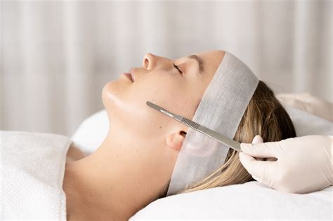 Aesthetician performing a dermaplaning procedure on a client's face.