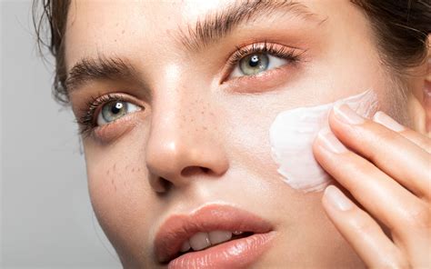 Close-up of a person applying moisturizer to their face