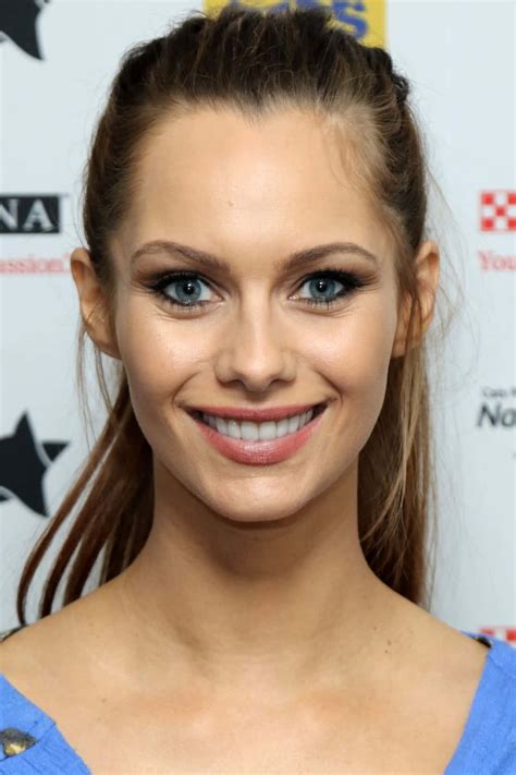 A woman smiling in a blue dress, with complementary makeup.