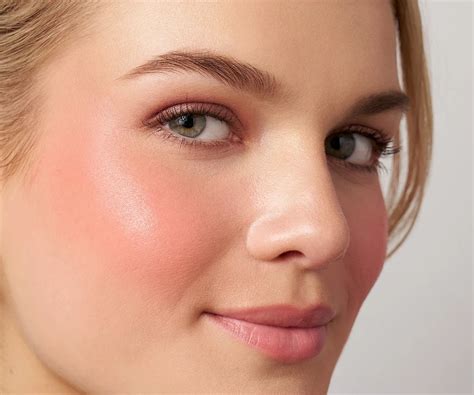Close-up of a woman's cheek with a coral blush applied.