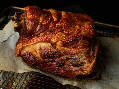 A whole roasted pork shoulder with a golden-brown, crispy skin, ready to be carved.