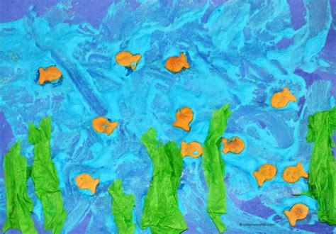 Child's puffy paint ocean craft with goldfish crackers and tissue paper seaweed