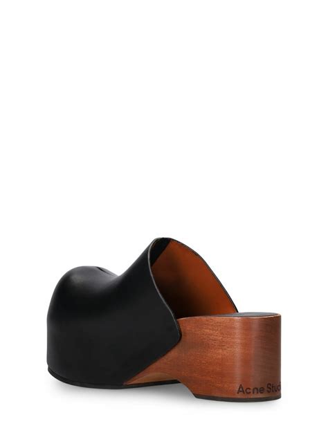 An artistic shot showcasing a pair of Acne Studios clogs with a focus on their texture and silhouette.