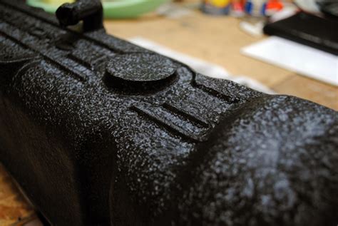 Close-up of a rocker cover being painted with wrinkle finish paint, showing the texture forming